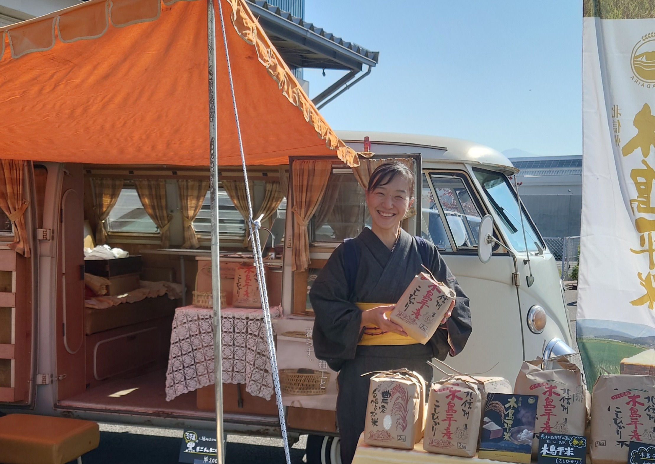 トップ画像 移住者インタビュイーが着物を着て木島平米を笑顔でPRしている様子