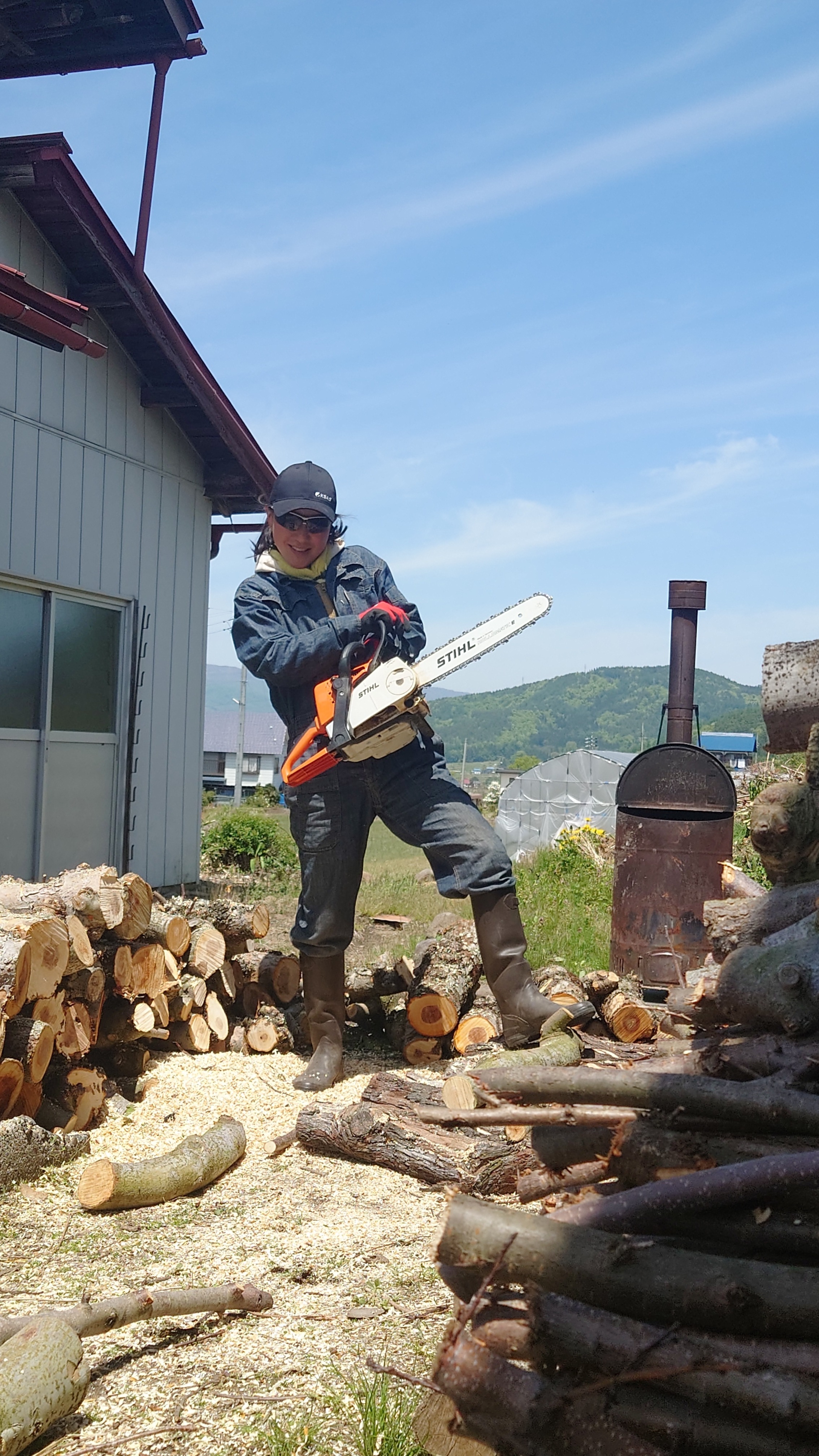 chainsaw 女性が薪ストーブ用の木材を切るためにチェーンソーを構えている様子