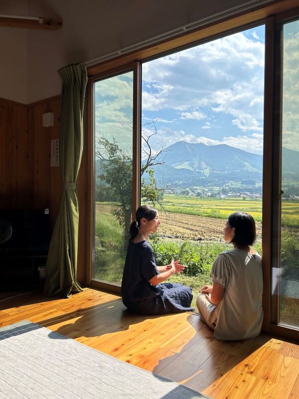 木島平村田舎暮らし体験住宅の窓辺に腰かけた2人の女性が楽しそうに話している様子