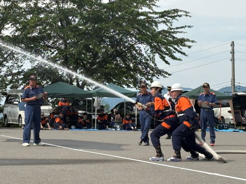 木島平村消防団員がポンプ車の水を放水している写真