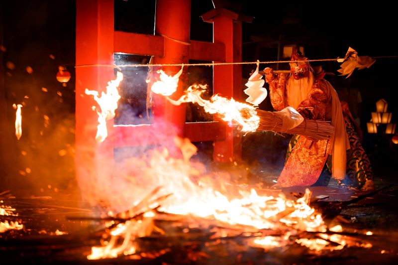 木島平村の秋祭りで天狗役がしめ縄を松明で焼き切っている写真