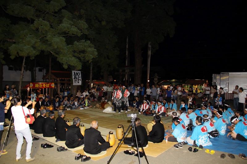 木島平村秋祭りの獅子舞奉納を観客と祭典団のメンバーが囲んでいる写真